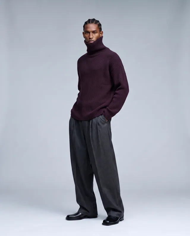 Aubergine Column — Cool-gray fashion studio with an architectural aubergine funnel neck and long charcoal tailoring.
